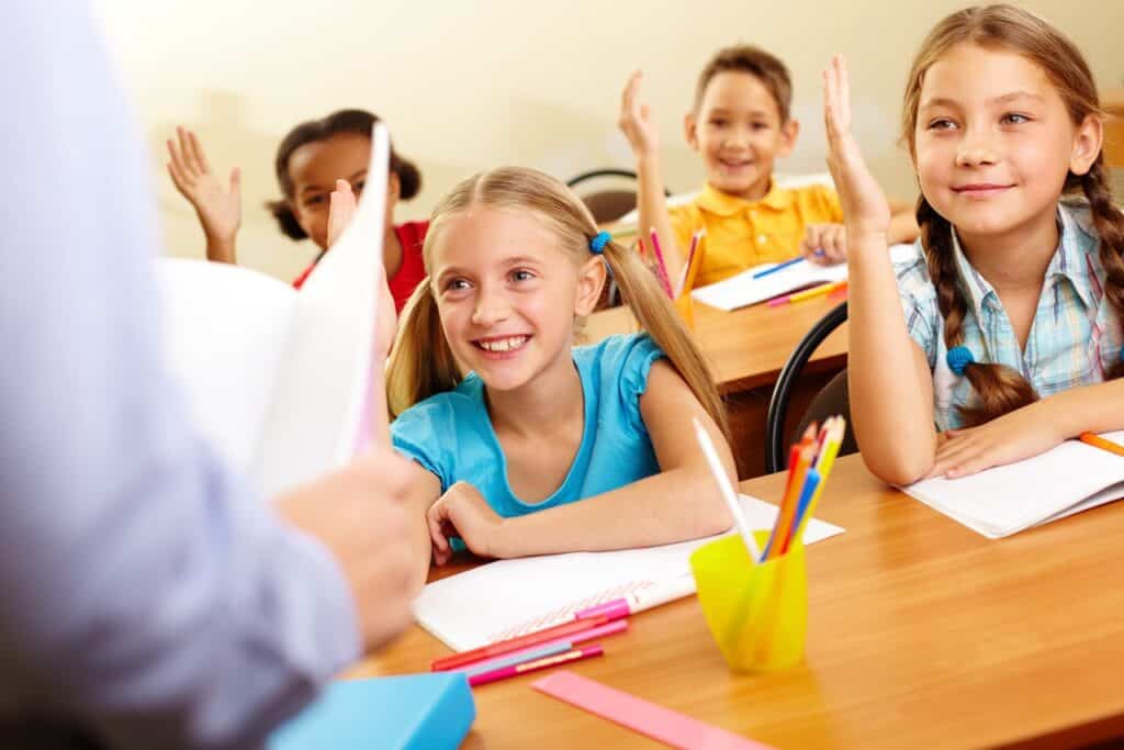 Image of students raising hands in classroom